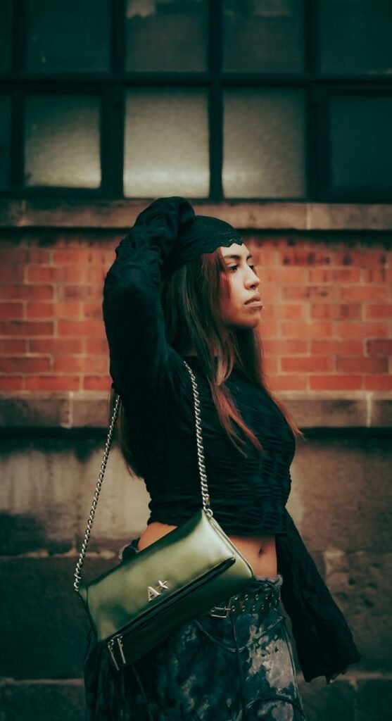 Fashionable woman posing against a brick wall, showcasing urban street style.